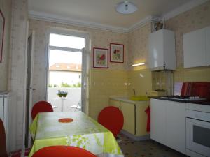 a kitchen with a table and red chairs and a kitchen with a window at Appartement Hello in Metz