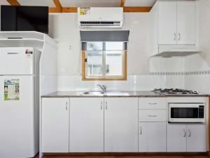 a white kitchen with a sink and a refrigerator at Canberra Holiday Village in Canberra