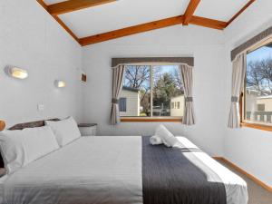 a bedroom with a large bed and two windows at Canberra Holiday Village in Canberra