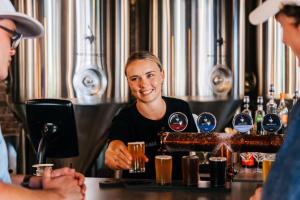 Una donna seduta al bar con un barista. di Habitat Noosa a Cootharaba