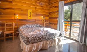a bedroom with a bed in a room with wooden walls at Del Milagro Cabañas & Posada in Villa General Belgrano +22 photos