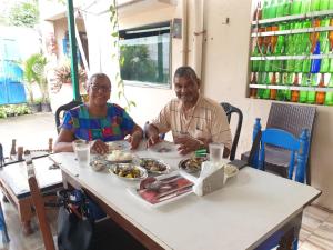 a man and a woman sitting at a table with food at Dream Vision Guest House in Diu