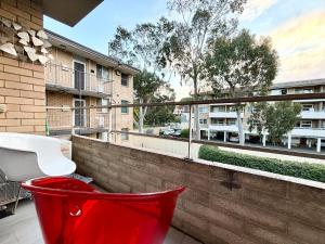 a red chair sitting on the balcony of a building at Central Subiaco Oasis 1 Bedroom Unit in Perth