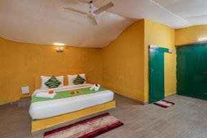 - une chambre avec un lit dans une pièce aux murs jaunes dans l'établissement Arise Ethnic Village Resort - Manesar Bilaspur, à Gurgaon 47 autres photos