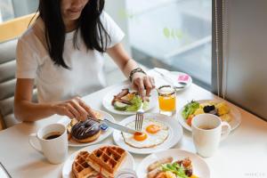a woman sitting at a table with breakfast food at Aloft Kuala Lumpur Sentral in Kuala Lumpur