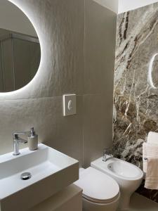 un bagno con lavandino, WC e specchio di Spinelli house a Napoli
