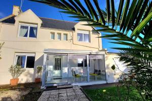 a white house with a palm tree in front of it at L'ESCAPADE BIGOUDENE - maison 300m de la plage in Tréffiagat