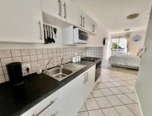 a kitchen with white cabinets and a sink at Escape to 205 in Stellenbosch central-free parking in Stellenbosch