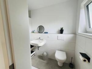 a white bathroom with a toilet and a sink at Deluxe in Burladingen