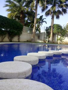 una fila de taburetes en una piscina con palmeras en Apartamento Migdia-Moraira, en Moraira