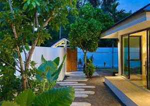 a garden with a pathway leading to a house at Brown Cotton Villa Khanom in Khanom