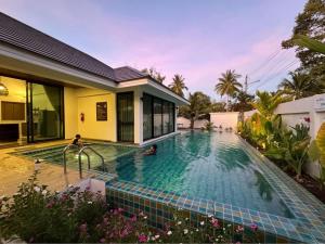 a swimming pool in front of a house at Brown Cotton Villa Khanom in Khanom