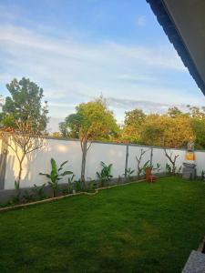 a backyard with a white wall and a green lawn at Me'Sari Guest House in Karangasem
