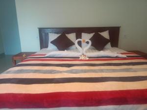 a large bed with two white pillows and two hearts at Me'Sari Guest House in Karangasem