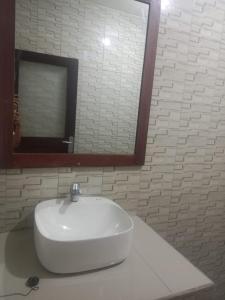 a white sink in a bathroom with a mirror at Me'Sari Guest House in Karangasem