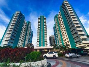 three tall buildings with cars parked in a parking lot at HELLAR Condo Rentals in Bacolod