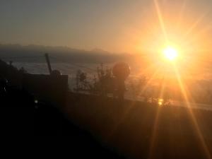 a sunset with the sun shining on a ship at Sunrise Point Homestay in Nagarkot