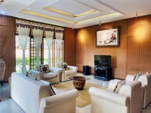 a living room with white chairs and a television at Villa Bango in Cilember Udik 1
