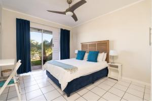 a bedroom with a bed with blue pillows and a window at Sea-Renity 10 in Umdloti
