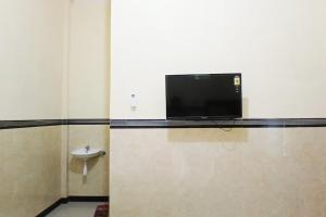 a bathroom with a tv on a wall with a toilet at RedDoorz at Dien Homestay Syariah Alun-alun Pasuruan in Krampijangan +23 photos