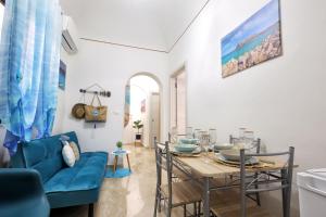 a living room with a table and a blue couch at La Piazzetta Del Tramonto Vista Mare In Centro in Trapani