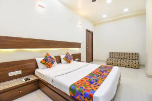 a bedroom with a bed and a chair in it at FabHotel Royal Suits - Nr Mahadji Shinde Chhatri in Pune