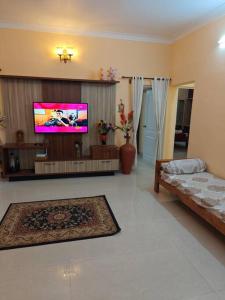 a living room with a flat screen tv and a couch at Ac 3 Bedroom House Mysore in Mysore