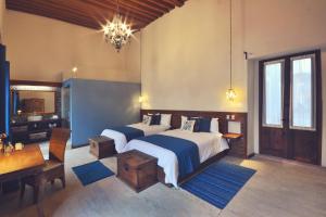 a bedroom with two beds and a table and a mirror at Hotel Boutique Casa Altamira in Querétaro