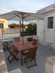 a wooden table with an umbrella on a patio at casa gialla mare del salento in Maruggio