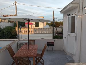 a table and chairs with an umbrella on a balcony at casa gialla mare del salento in Maruggio