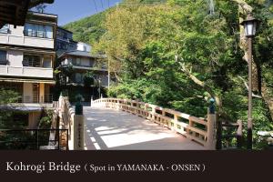 a wooden bridge over a road in a city at Yamanaka Onsen Kagari Kisshotei in Kaga