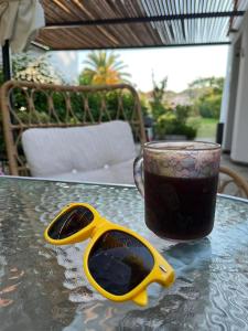 a cup of coffee and a pair of sunglasses on a table at Andromeda Shell House in Pefkochori