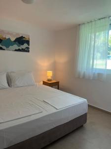 a bedroom with a white bed and a window at Andromeda Shell House in Pefkochori