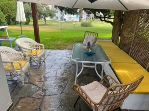 a table and chairs on a patio under an umbrella at Andromeda Shell House in Pefkochori