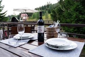 a wooden table with a bottle of wine and glasses at Holiday House Tjaša in Lokve