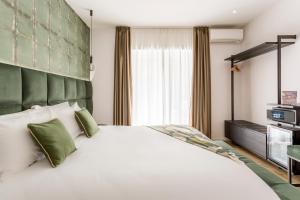 una camera da letto con un grande letto bianco con accenti verdi di Romi Suite a Roma