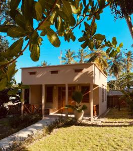 a small white house with a palm tree at Dive Planet Mafia Island in Utende