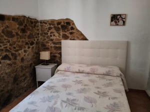 a bedroom with a bed in a room with a stone wall at Casa rural Alicia in Cortegana +21 photos