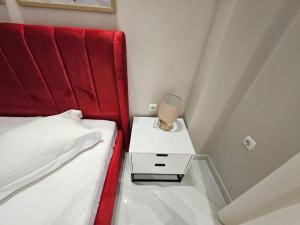 Un dormitorio con un cabecero rojo y una cama blanca con una mesa de cristal. en Agora luxury Studio 4, en Loutraki