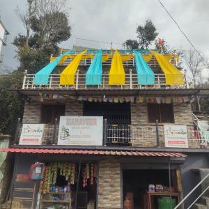a building with blue and yellow umbrellas on top of it at The lap of himalayas homestay in Pokhri