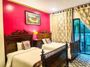 a bedroom with two beds and a red wall at สงขลาแต่แรก แอนทีค โฮเท็ล Songkhla Tae Raek Antique Hotel in Songkhla