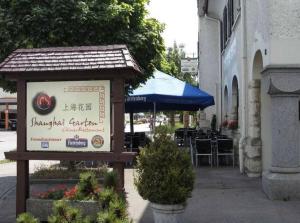 a sign in front of a restaurant with tables and chairs at Hotel Restaurant Shanghai Garten in Klettgau