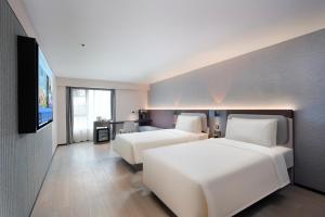 Una habitación de hotel con dos camas y un televisor de pantalla plana. en Atour Light Hotel Nanjing Chengxin Avenue Subway Station, en Jiangning