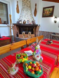a table with two rabbits and fruit on a table with a fireplace at Sunny Guest House in Boykovtsi