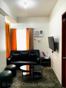 a living room with a black leather couch and a television at HELLAR Condo Rentals in Bacolod