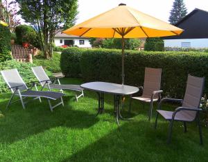 una mesa y sillas con una sombrilla en la hierba en Gästehaus Helga Scherer, en Ballrechten 5 fotos más