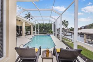 a swimming pool with two chairs and a table with a table at Alluring waterfront home with W exposure, pool/dock in Marco Island