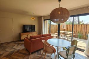 een woonkamer met een bank en een tafel bij Villa IrisJasmin jacuzzi vue mer in Lacanau