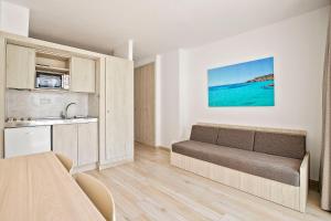 a living room with a couch and a kitchen at Sunside Ibiza Studios - Only Adults- Formerly known as Central Park in San Antonio