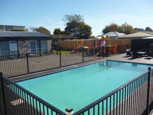una piscina en un patio con parque infantil en Cashel Court Motel, en Christchurch